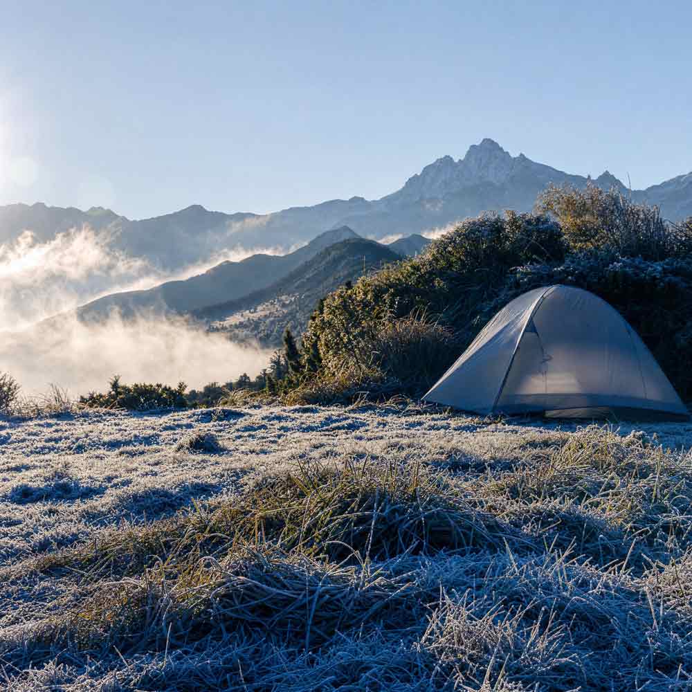 Camping tent in a frosty mountain landscape with snow and mist.